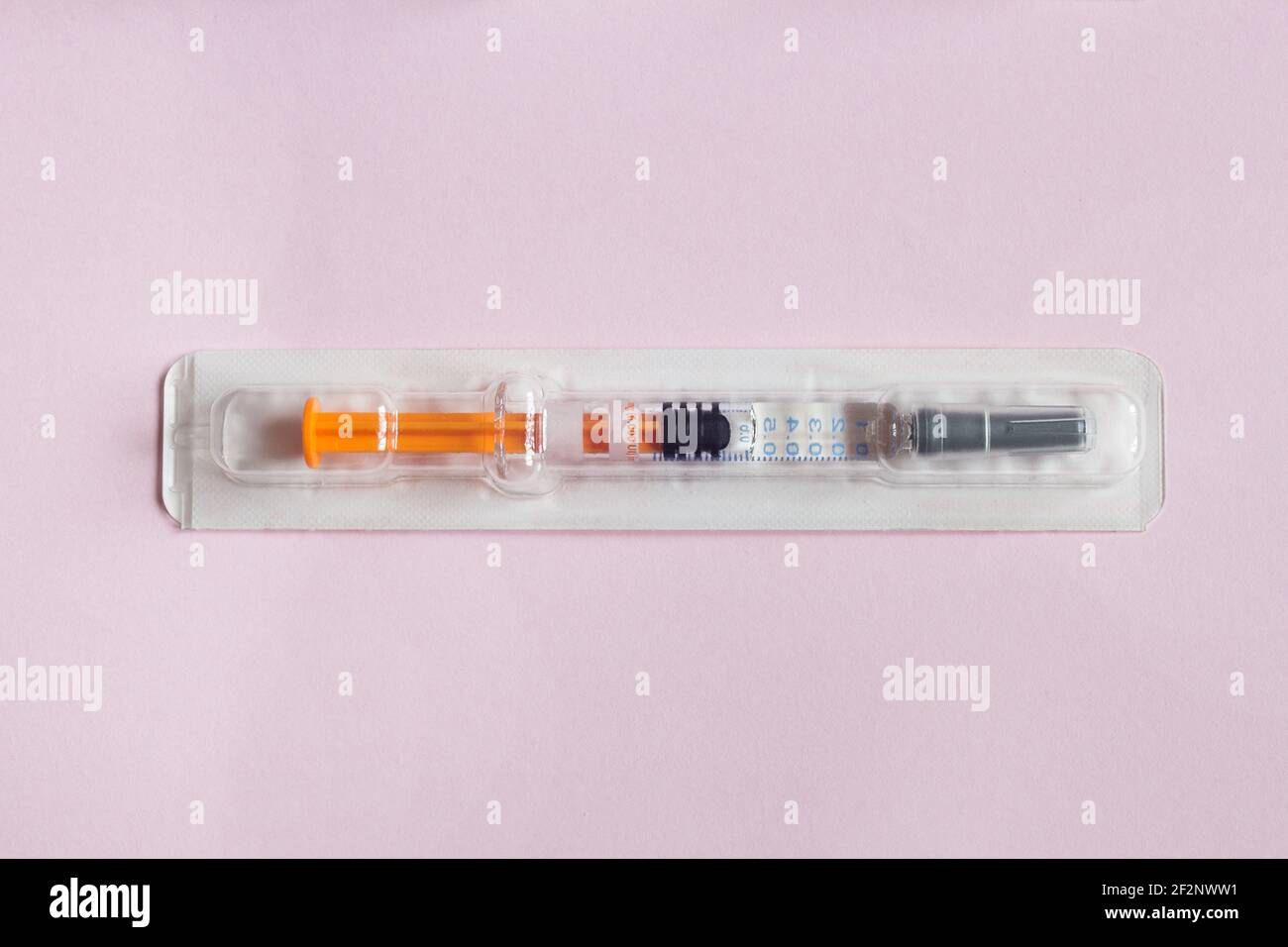 Siringa sigillata singolarmente pre-riempita con una soluzione medica in un blister di plastica su uno sfondo di carta rosa testurizzata. Scienza salute e medicina. Foto Stock