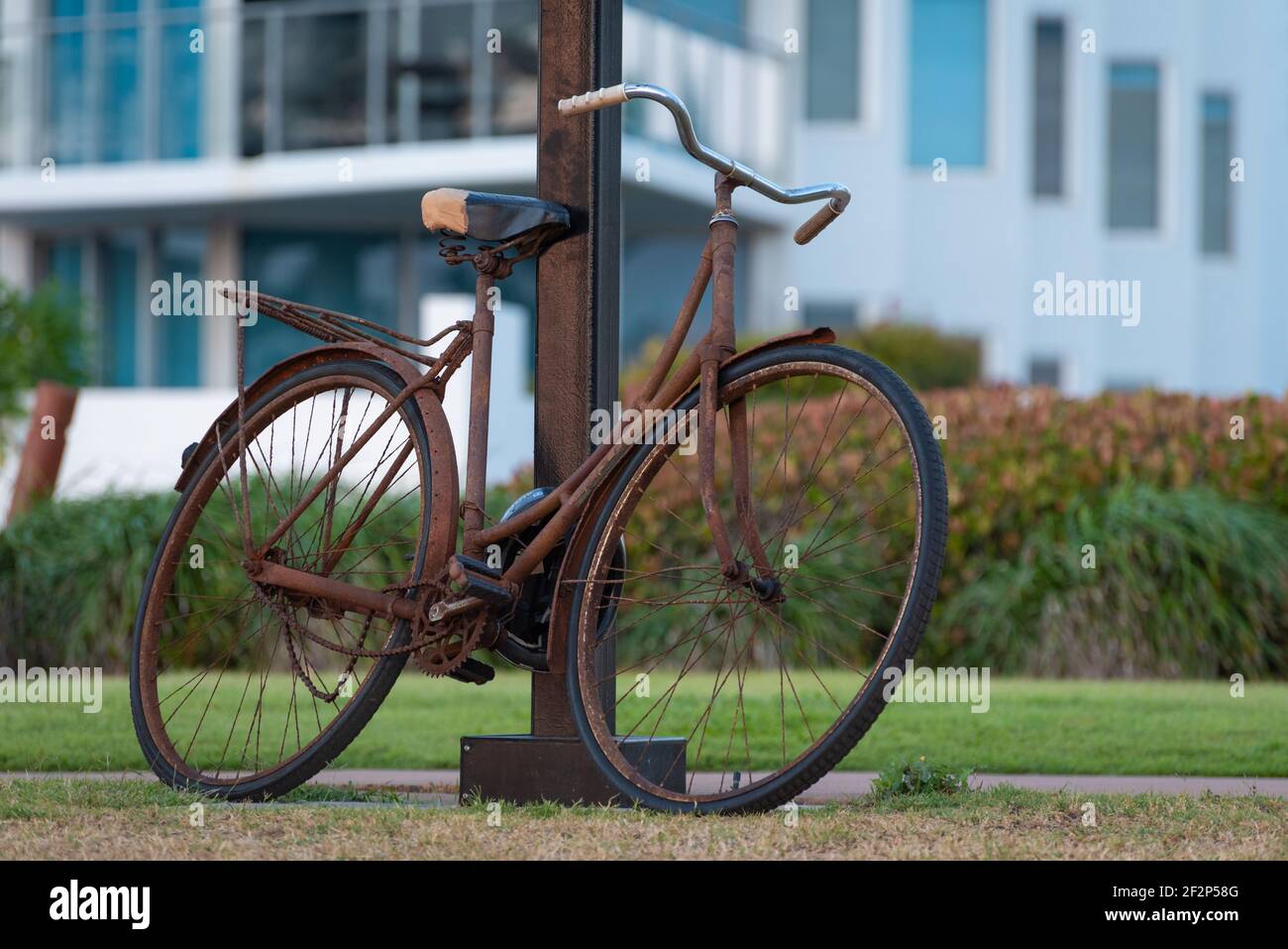 Una vecchia bicicletta arrugginita si appoggia contro un lampione Foto Stock