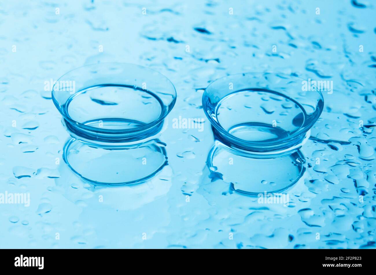 Lenti a contatto con gocce su sfondo blu lucido. Foto Stock
