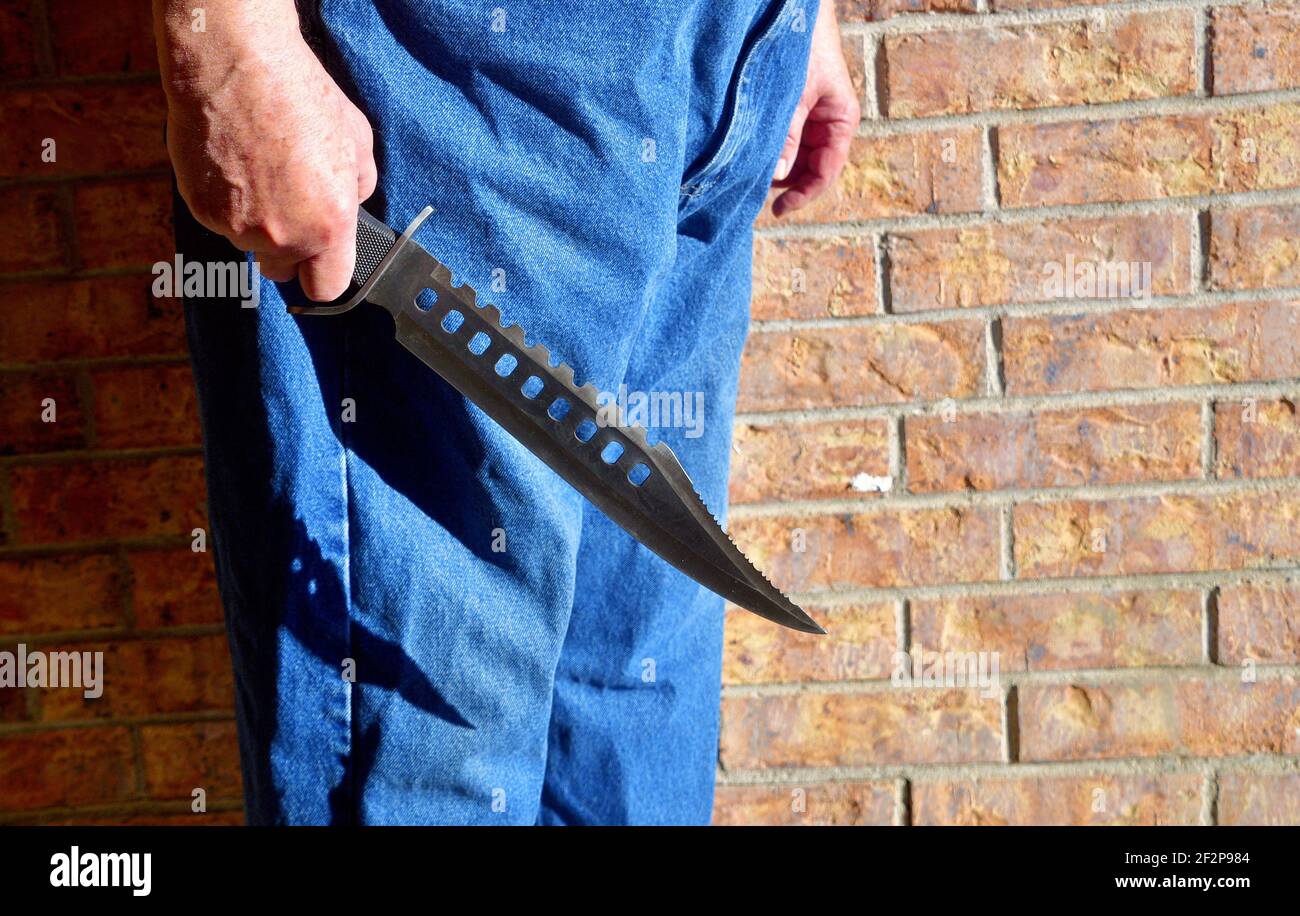 Un grande coltello Bowie in mano a un maschio maturo; crimine violento o concetto di terrorismo Foto Stock