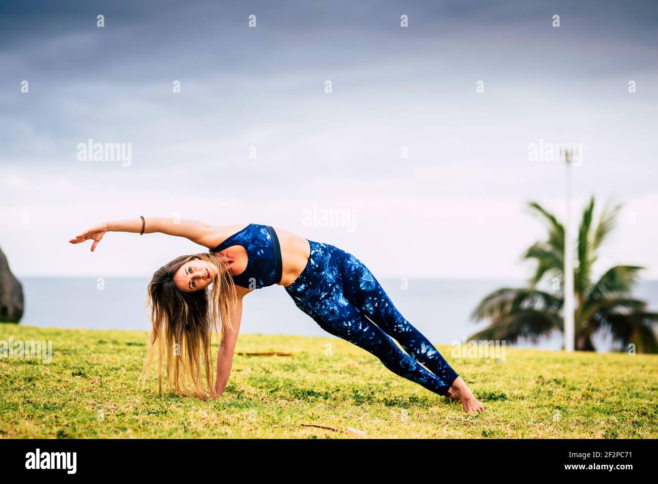 Bella giovane donna adulta in equilibrio pilates posizione di esercizio all'aperto - sport persone attive e sano stile di vita concetto - allegro caucasica femmina do yoga Foto Stock