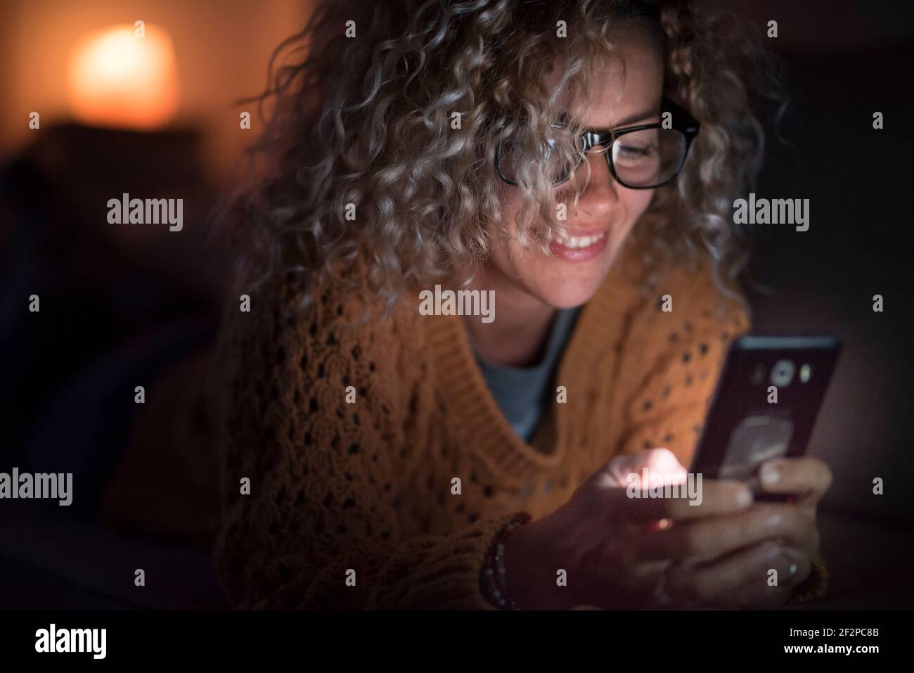 Donna adulta utilizzare il telefono cellulare Internet di notte da solo a. casa - persone e dipendenza dalla tecnologia - connessione e. concetto di conferenza telefonica - consente di cercare il web femminile con occhiali Foto Stock