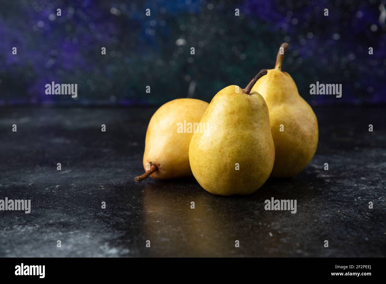 Tre gustose pere gialle poste sulla superficie nera Foto Stock