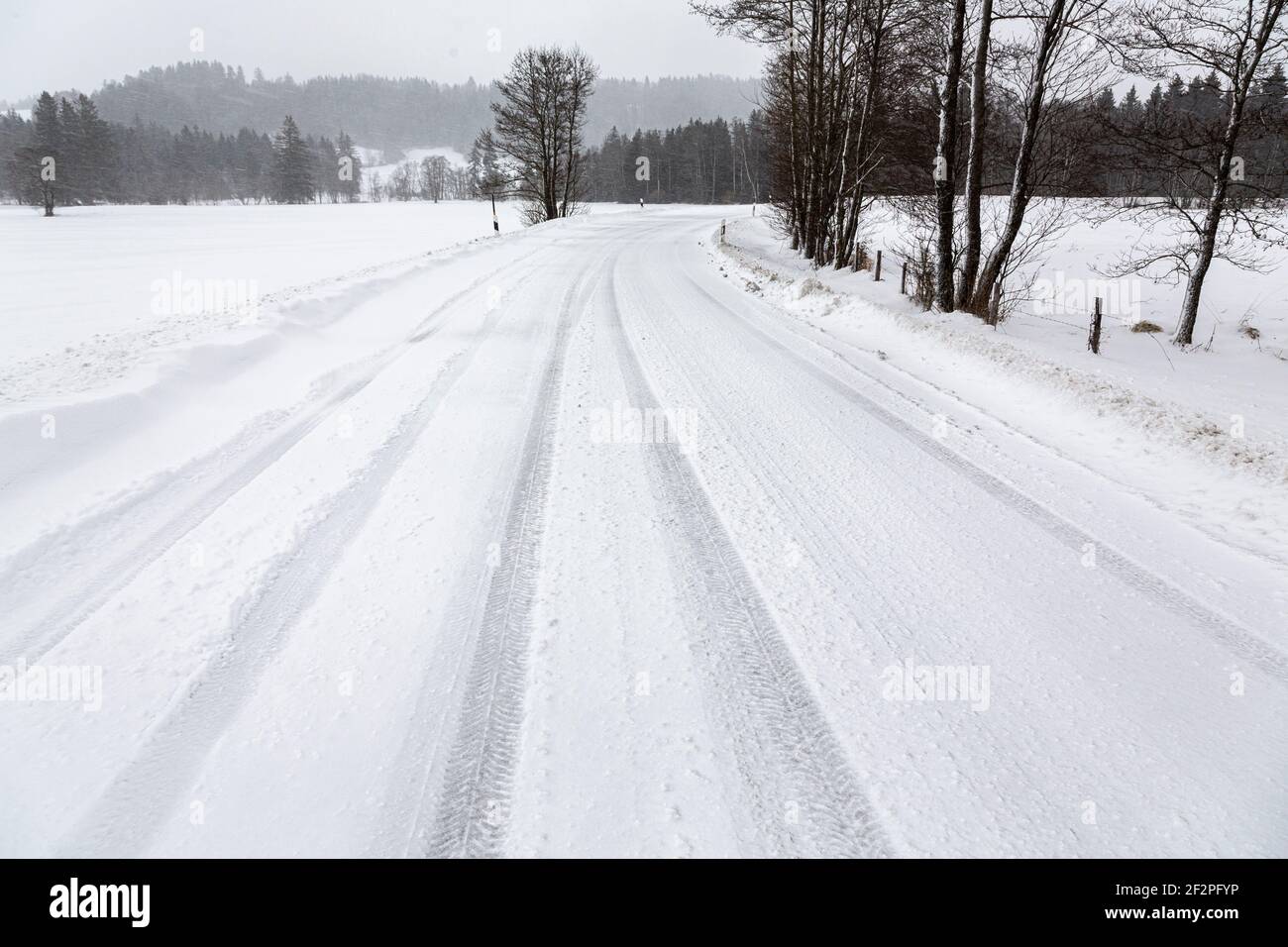 Germania, Baviera, strada di campagna innevata con cingoli pneumatici. Foto Stock