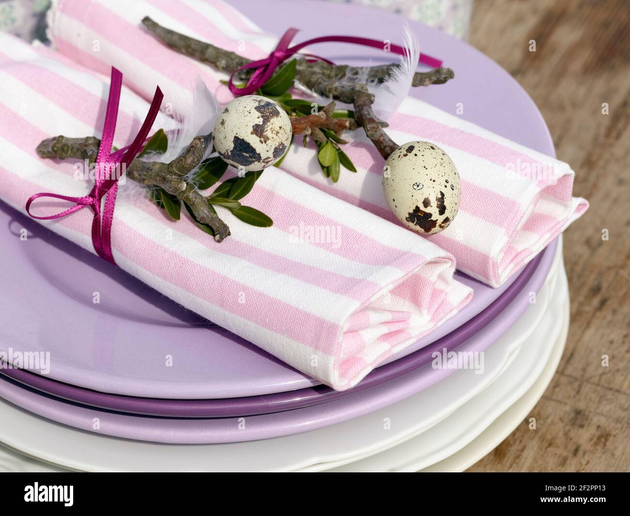 Colazione di Pasqua, due tovaglioli di stoffa, decorati con ramoscelli e  uova di quaglia impalate su di loro, circondati da un nastro viola su una  pila di piatti Foto stock - Alamy