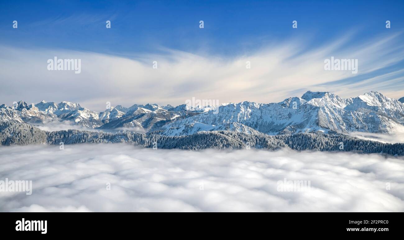 Paesaggio di montagna innevato su copertura nuvolosa in una giornata invernale soleggiata. Alpi di Allgäu, Baviera, Tirolo, Germania, Austria Foto Stock