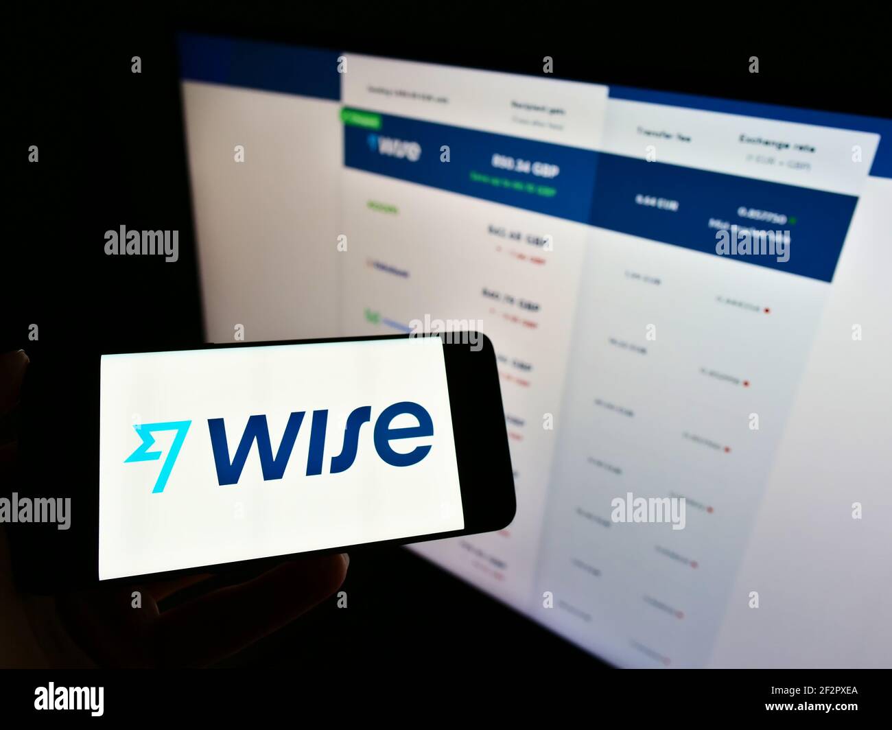 Persona che tiene il telefono mobile con il logo della società di pagamento elettronica Wise (TransferWise Ltd.) sullo schermo davanti alla pagina web. Mettere a fuoco il display del telefono. Foto Stock