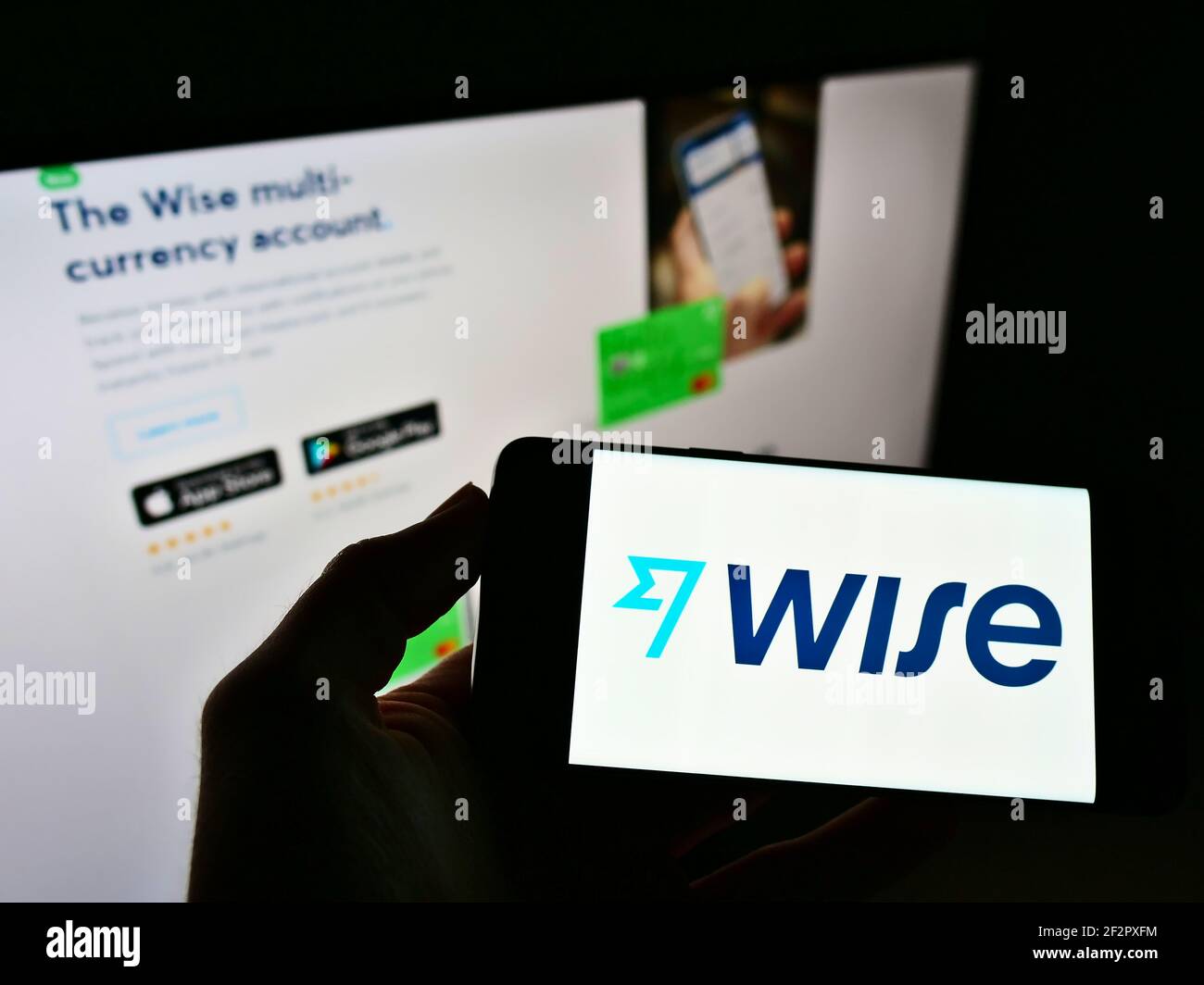 Persona che tiene lo smartphone con il logo della società di pagamento elettronica Wise (TransferWise Ltd.) sullo schermo di fronte al sito web. Mettere a fuoco il display del telefono. Foto Stock