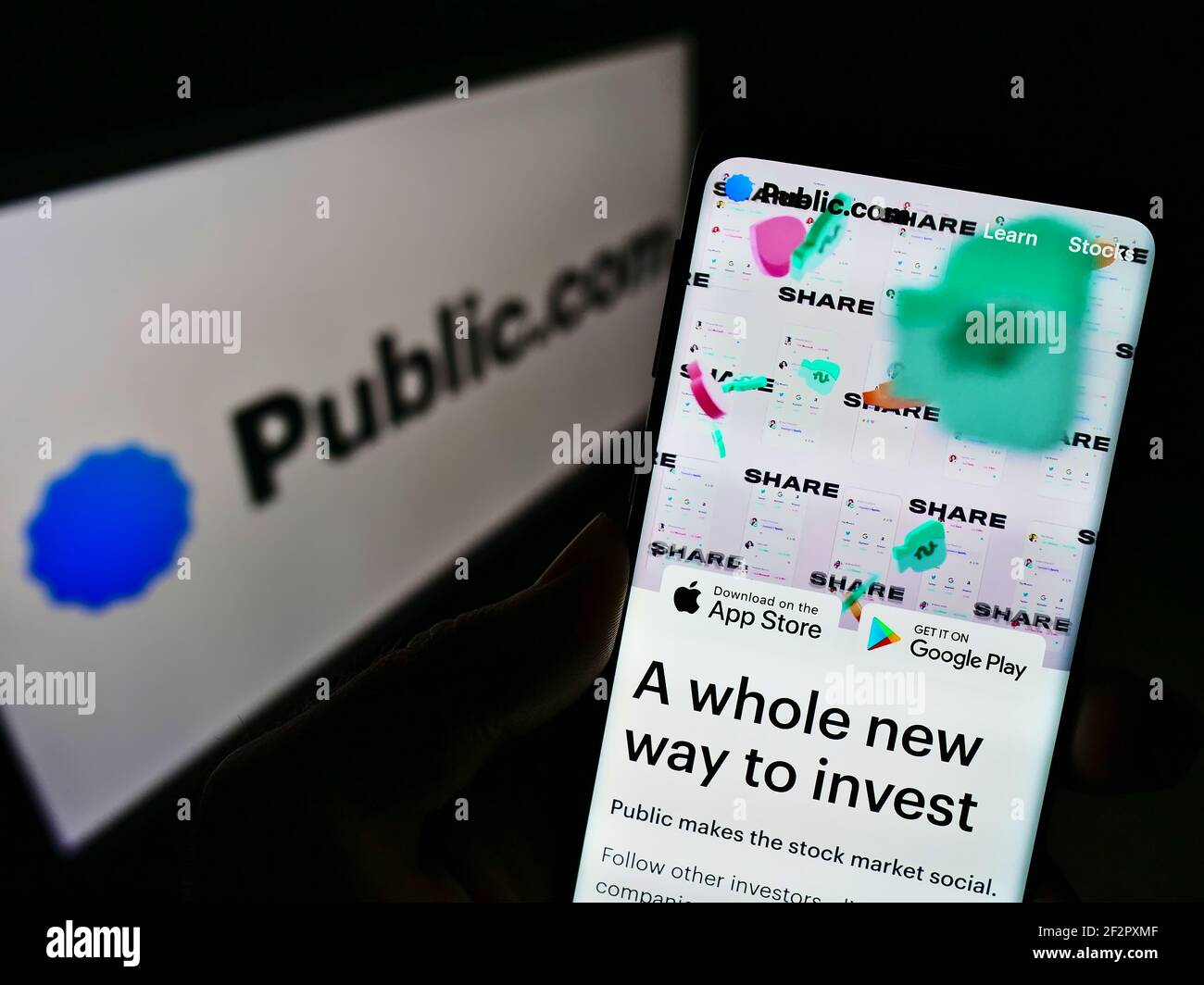 Persona in possesso di smartphone con sito web aziendale della piattaforma di investimento Public.com sullo schermo di fronte al sito web. Mettere a fuoco il centro del display del telefono. Foto Stock