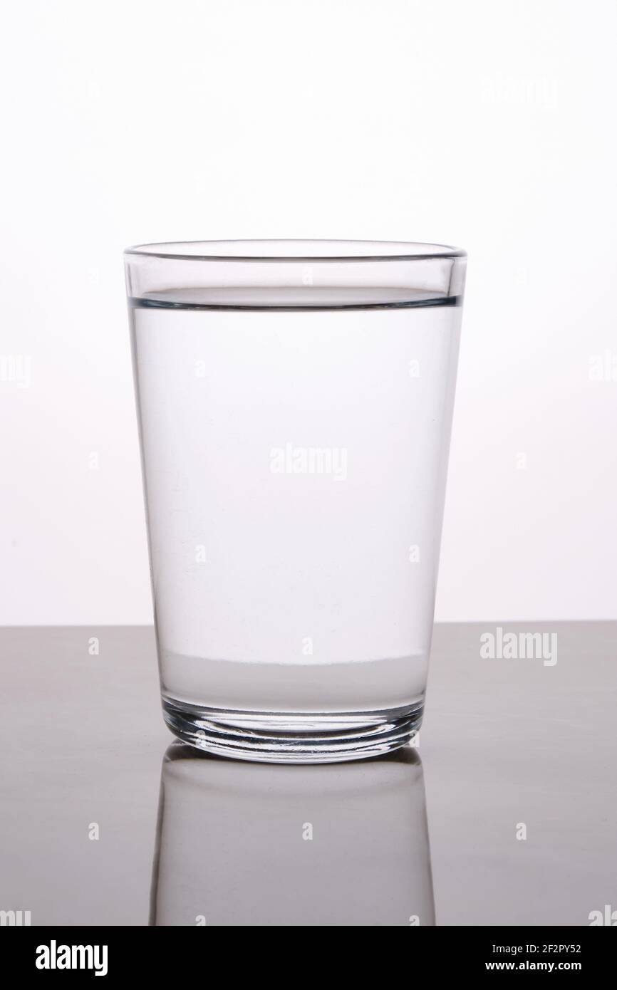 Vetro bianco d'acqua catturato con riflesso con retroilluminazione su sfondo chiaro Foto Stock