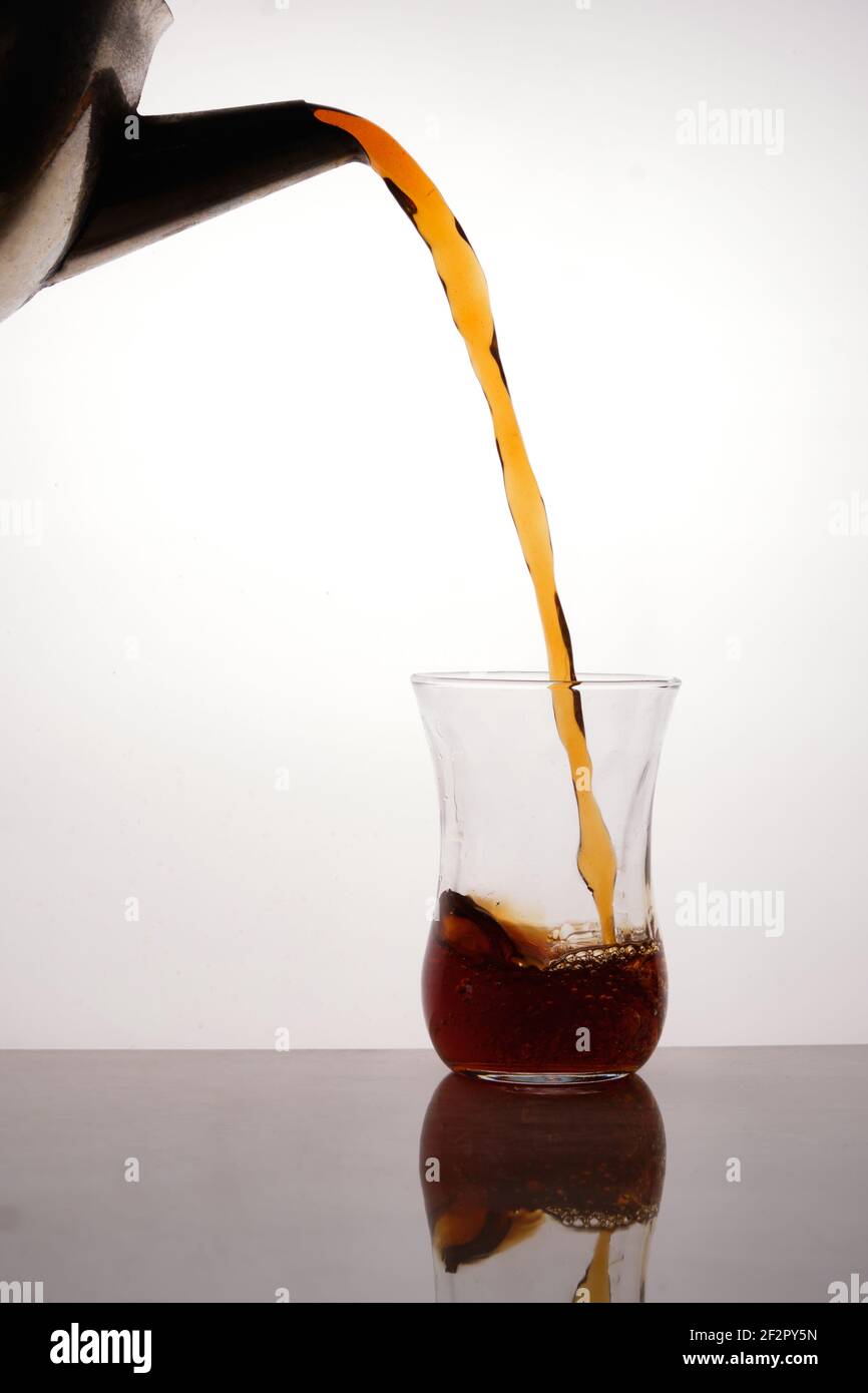 Il tè viene versato dalla teiera annerita al bicchiere di tè turco Foto Stock