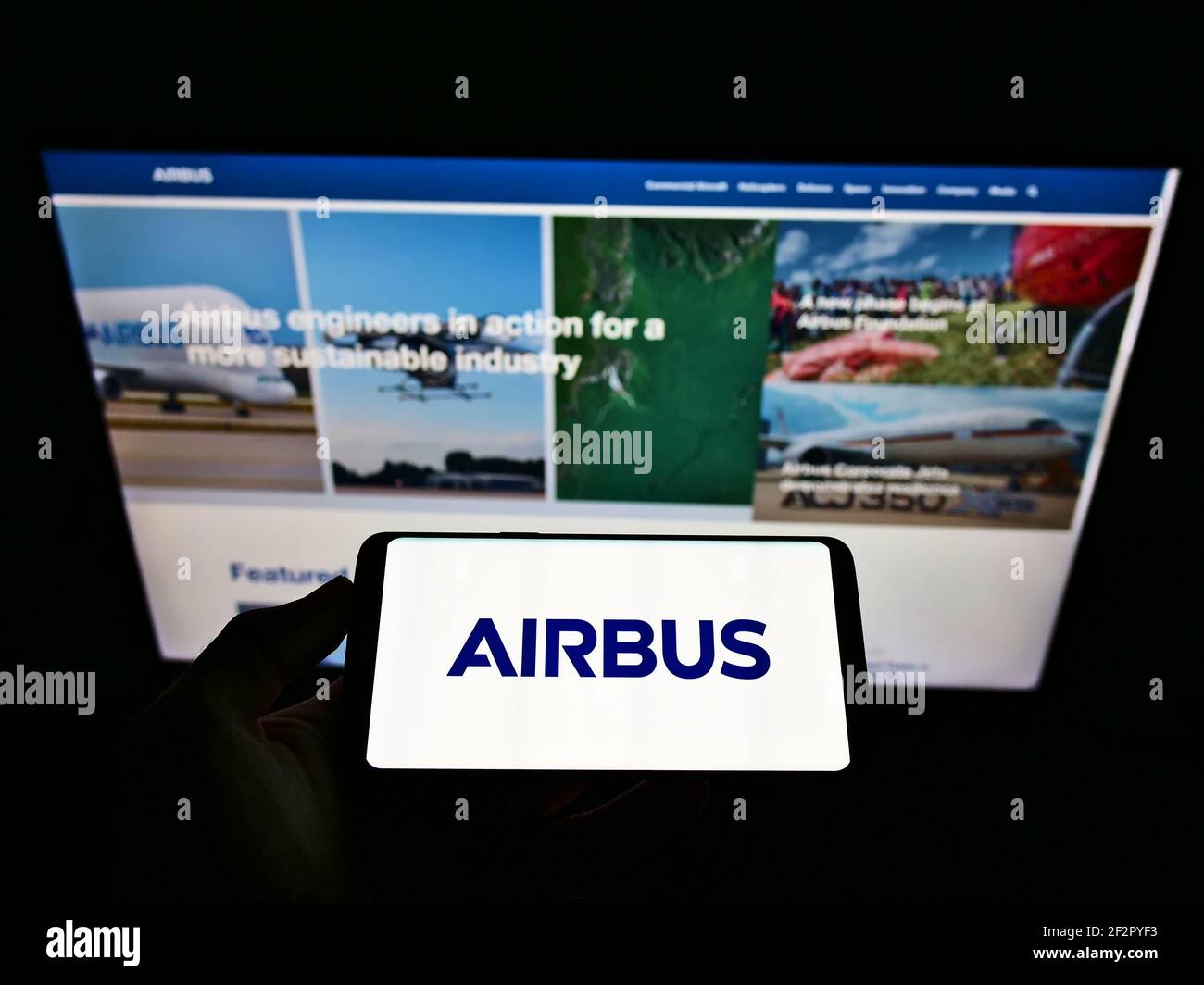 Persona che detiene smartphone con il logo aziendale del produttore di aerei Airbus se sullo schermo di fronte al sito Web aziendale. Mettere a fuoco il display del telefono. Foto Stock