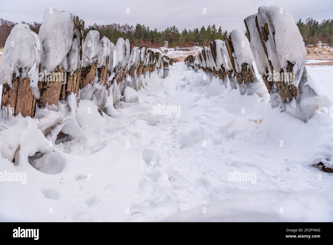 antico molo con ghiaccio coperto in inverno e mare acqua lavaggio le pile di legno è congelato Foto Stock