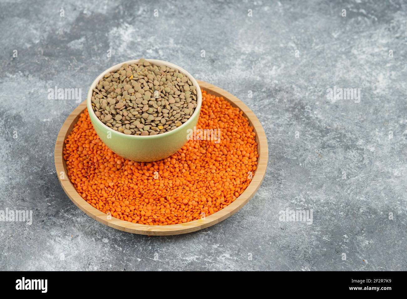 Lenticchie grezze rosse e piselli spezzati su sfondo marmoreo Foto Stock