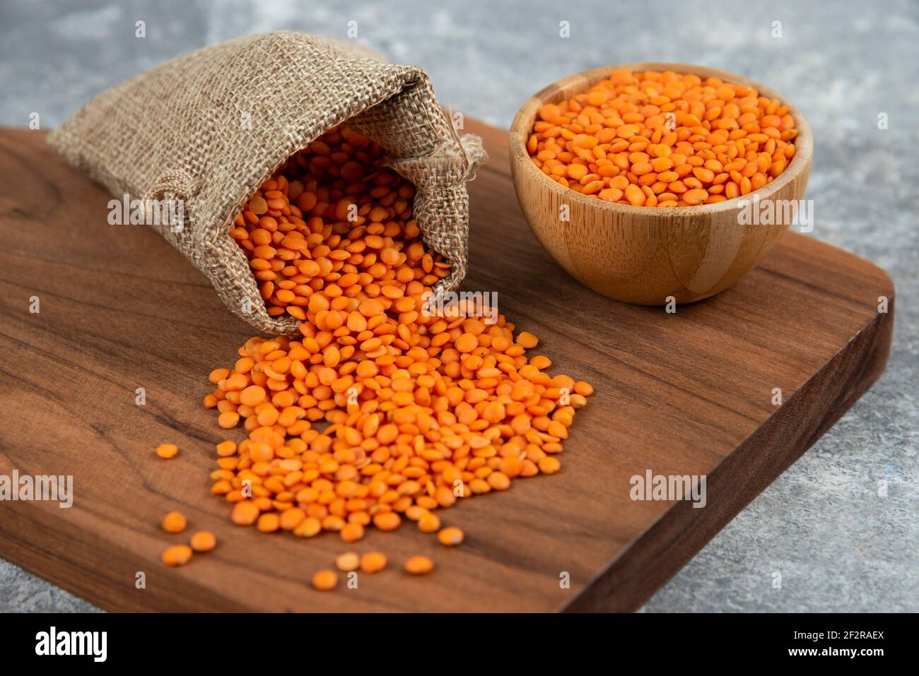 Ciotola e sackcloth di lenticchie grezze rosse su tavola di legno Foto Stock