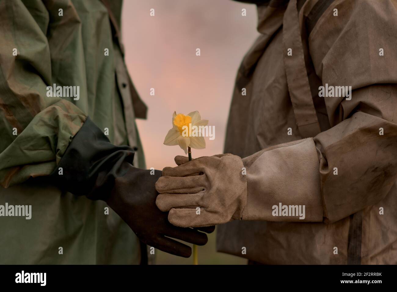 Un uomo e una donna in un vestito di protezione chimica. Post-apocalisse. Un uomo dà un fiore alla sua donna. Foto Stock