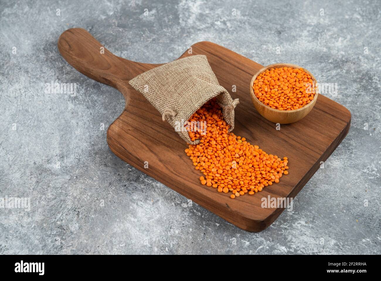 Ciotola e sackcloth di lenticchie grezze rosse su tavola di legno Foto Stock