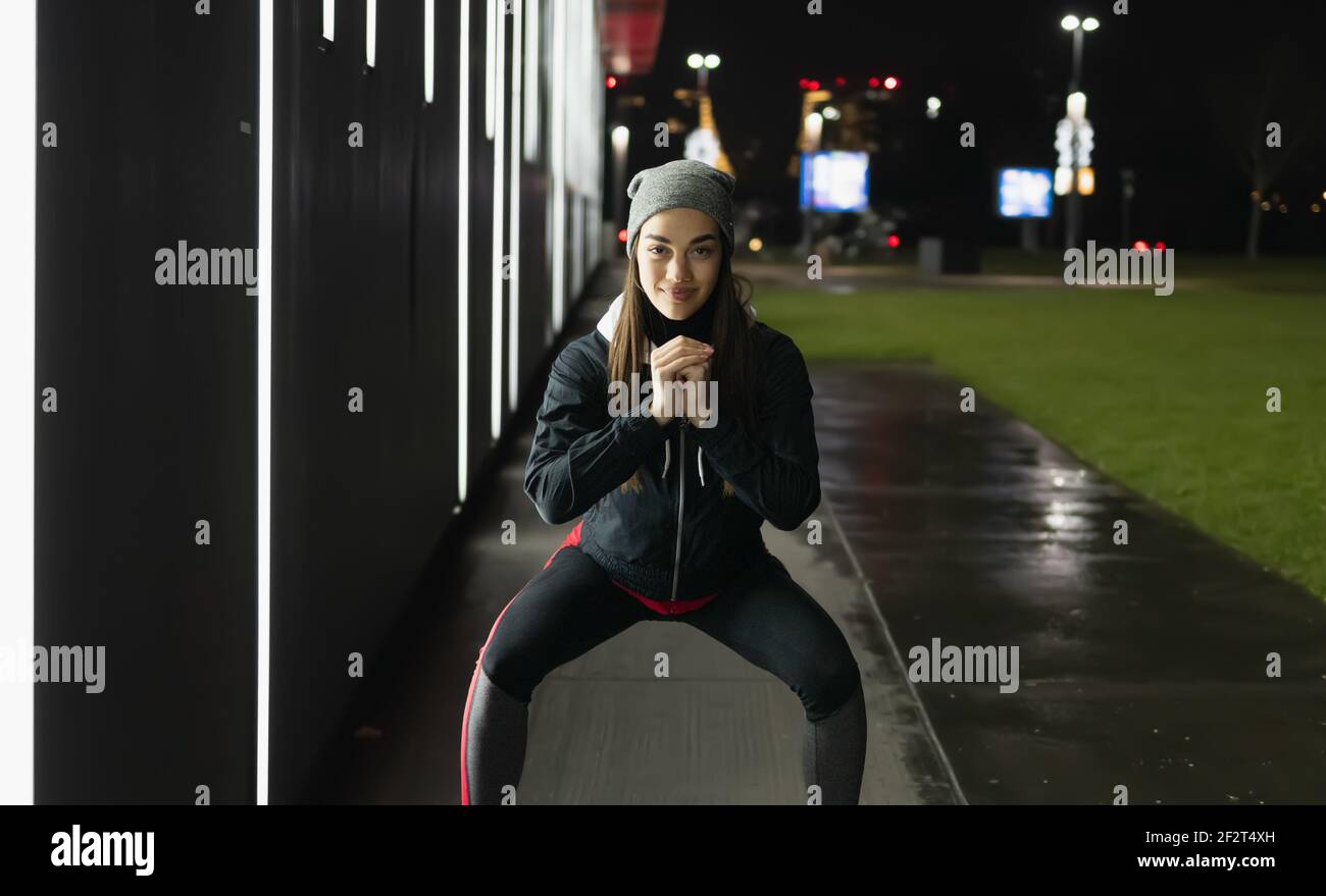 Il sorriso mentre si prepara per una corsa notturna intorno a. città Foto Stock