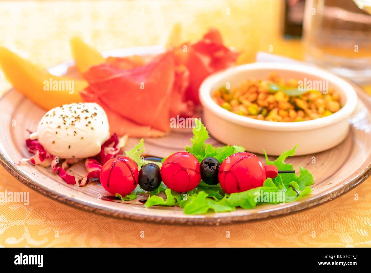 Classico antipasto italiano. Pomodori ciliegini italiani, mozzarella, melone con prosciutto italiano fuoco selettivo, primo piano. Foto Stock