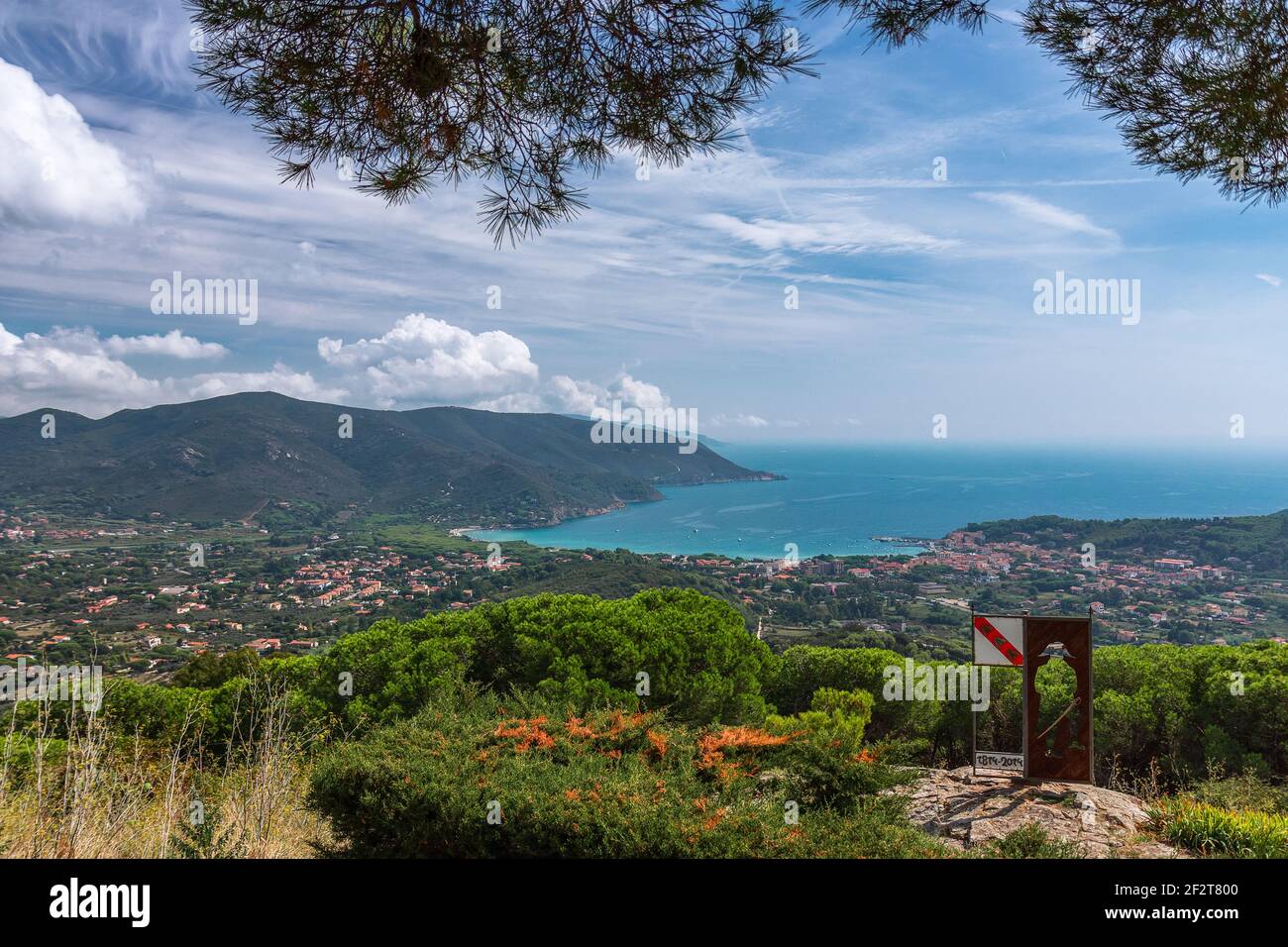 Vista panoramica di una delle spiagge dell'isola d'Elba e di un piccolo paese vicino alla spiaggia nella laguna di mare smeraldo. Toscana, Italia. Foto Stock