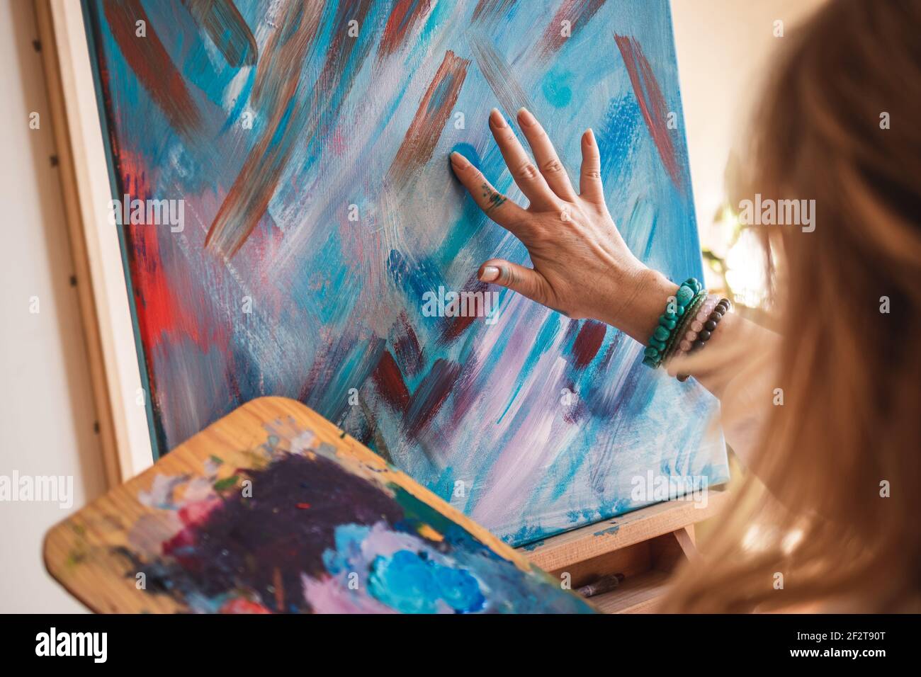 Dipinti astratti d'arte. Donna artista pittura su tela a mano e dito. Artista femminile che utilizza abilità e tecnica creativa Foto Stock