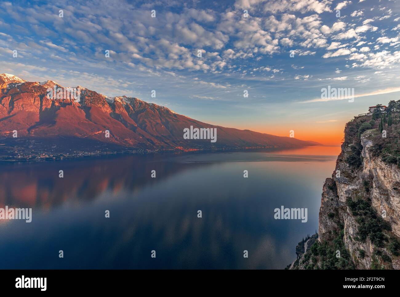 Tramonto mozzafiato sul Lago di Garda. Vista delle Alpi innevate dipinte dal sole tramontare dalla scogliera della città Tremosine. Periodo invernale. Lombardia, Italia Foto Stock