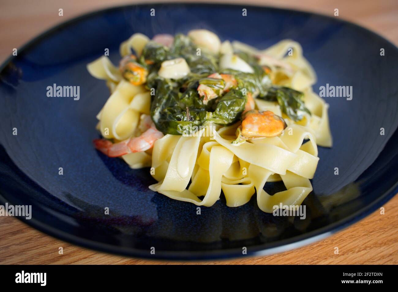 Fettuccine con salsa di crema di formaggio spinaci e pesce arrangiato una piastra Foto Stock