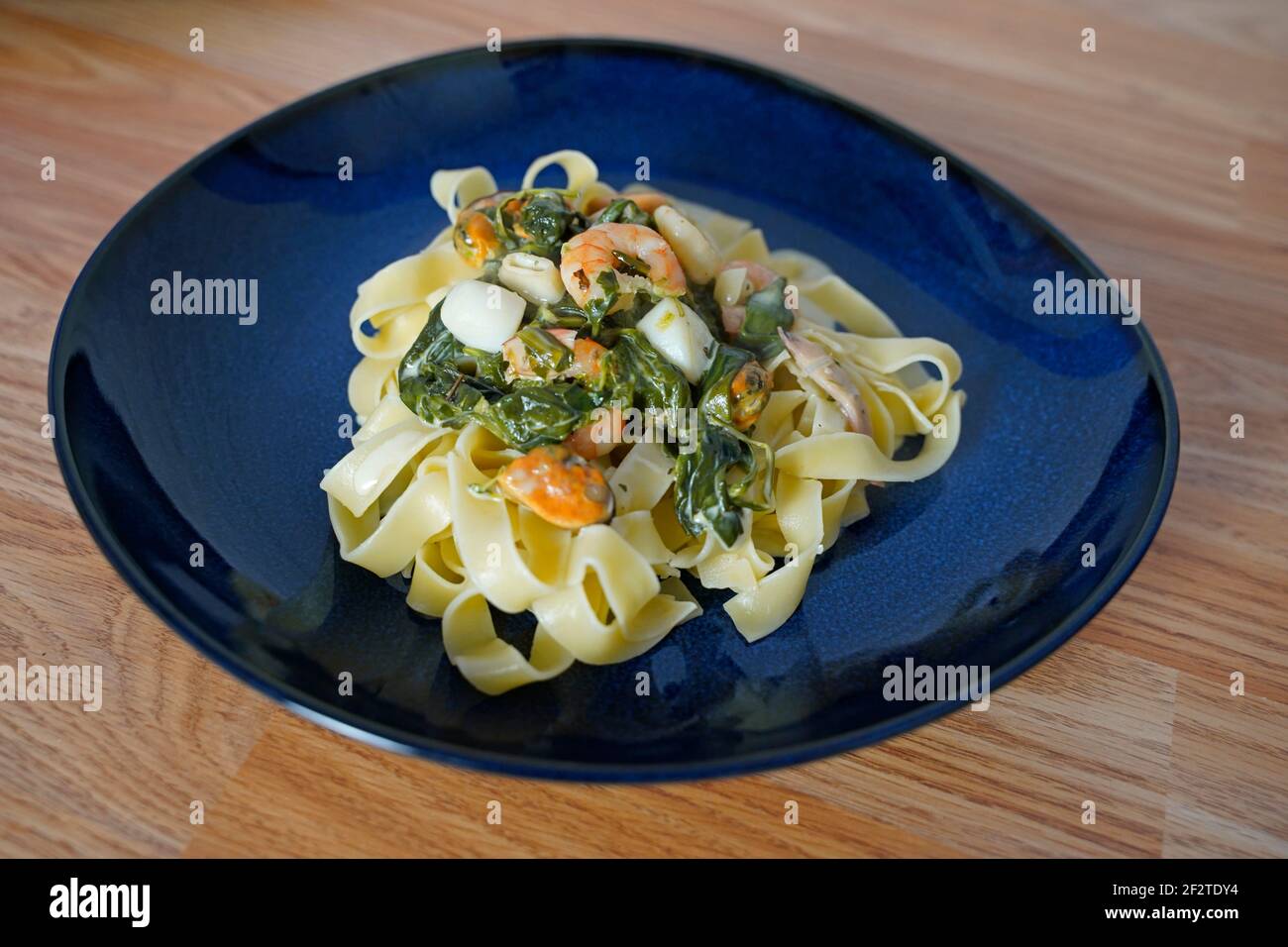 Fettuccine con salsa di crema di formaggio spinaci e pesce arrangiato una piastra Foto Stock