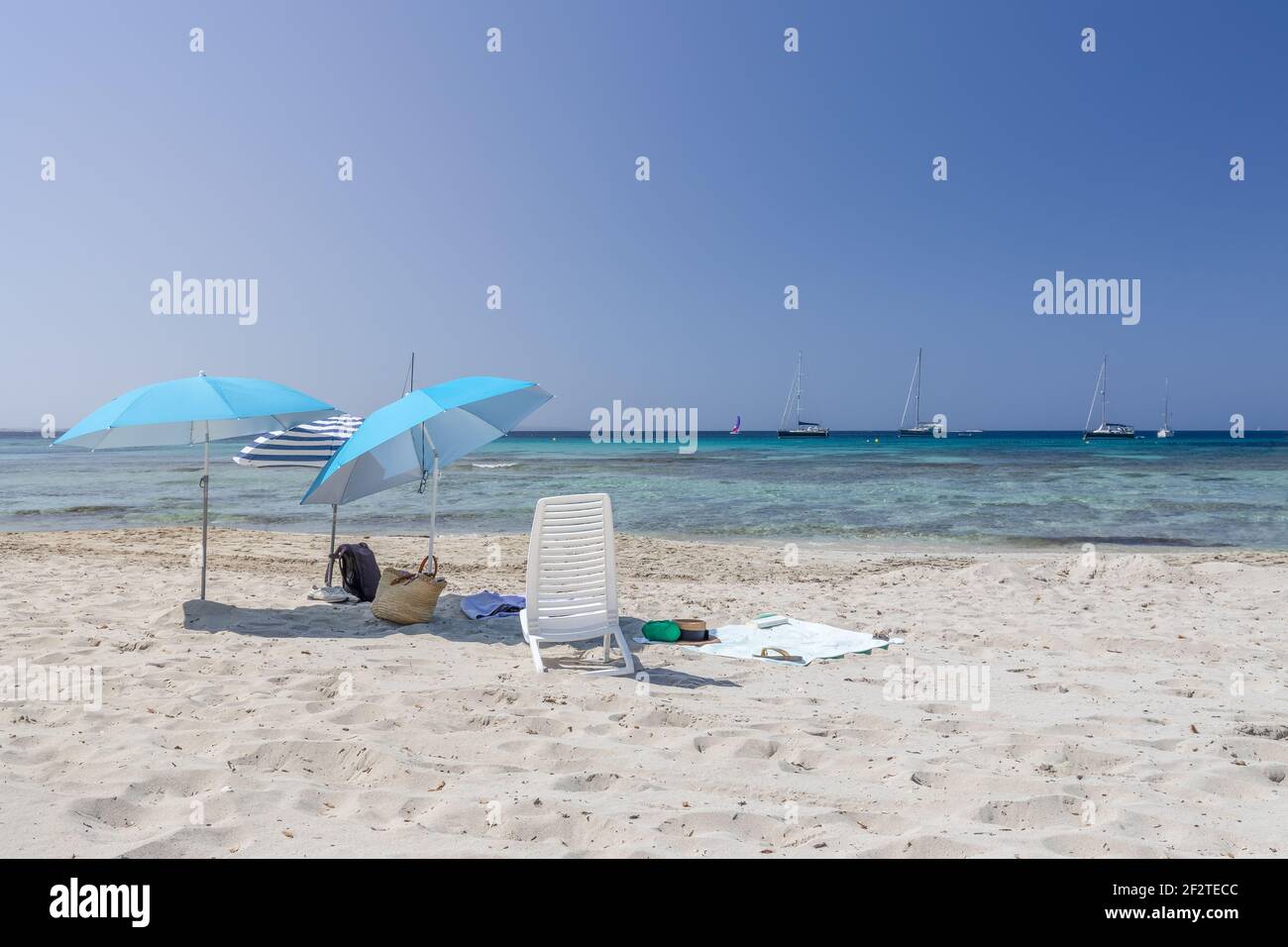 Mare con ombrelloni e mare turchese sulla spiaggia (Ses Salines) Isola di Ibiza, Isole Baleari. Spagna Foto Stock