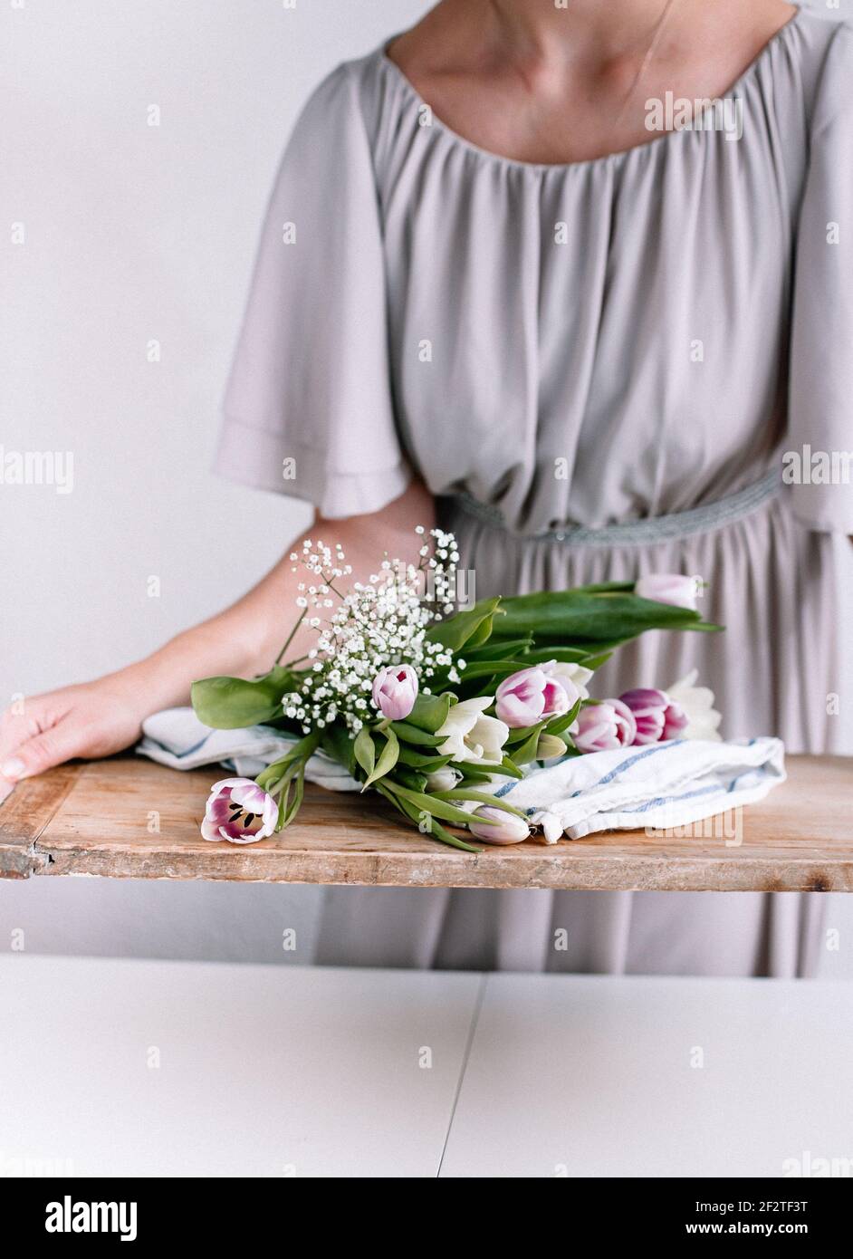 Bei tulipani su un tagliere di legno, umore nordico o vita nordica. La donna sta tenendo dei fiori per portare più cibo nordico. Foto Stock