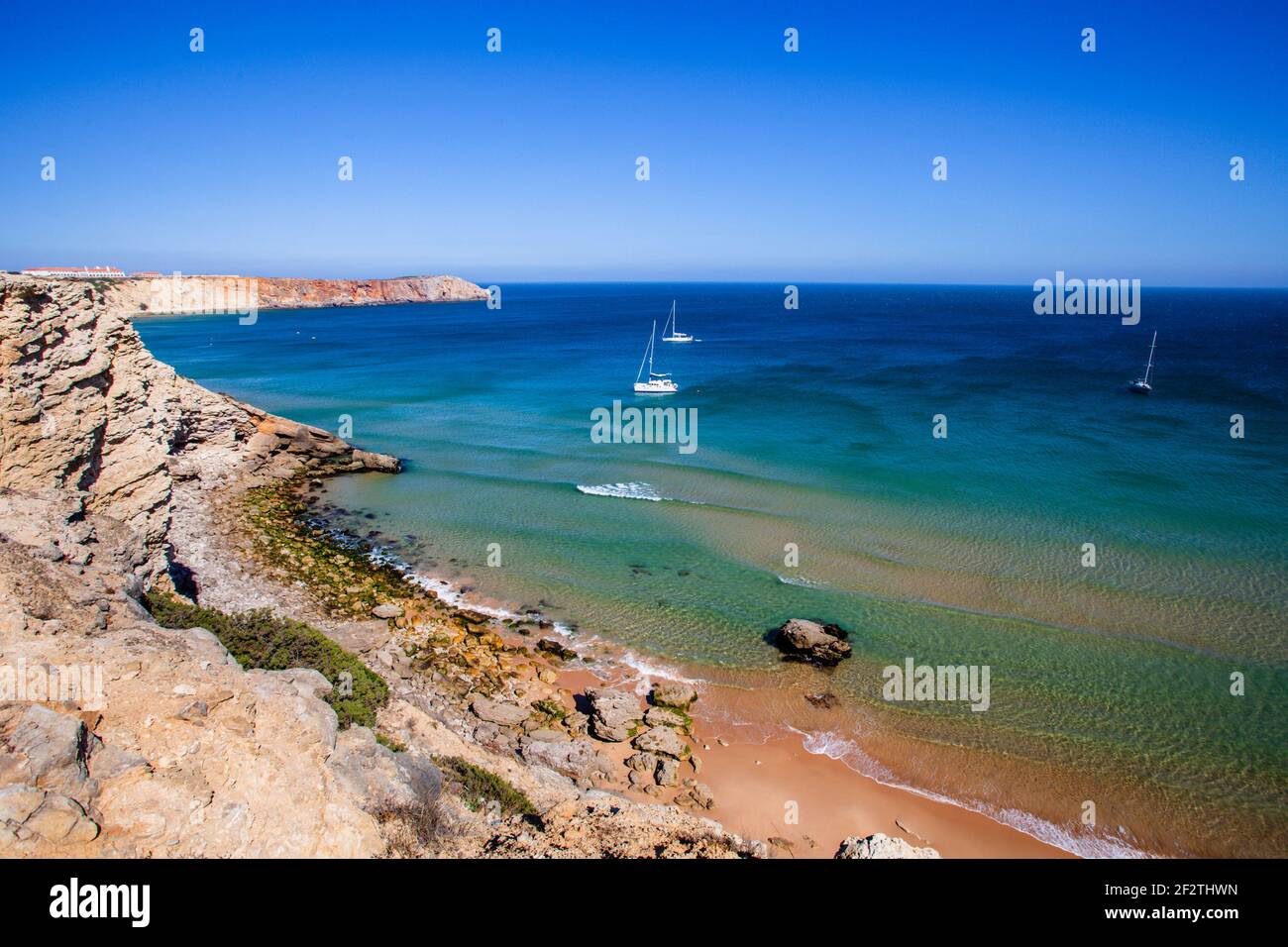 Piccole barche bianche che navigano lungo la costa tra la Fortezza di Sagres e Cap Saint Vincent, nell'Algarve, Portogallo. Foto Stock