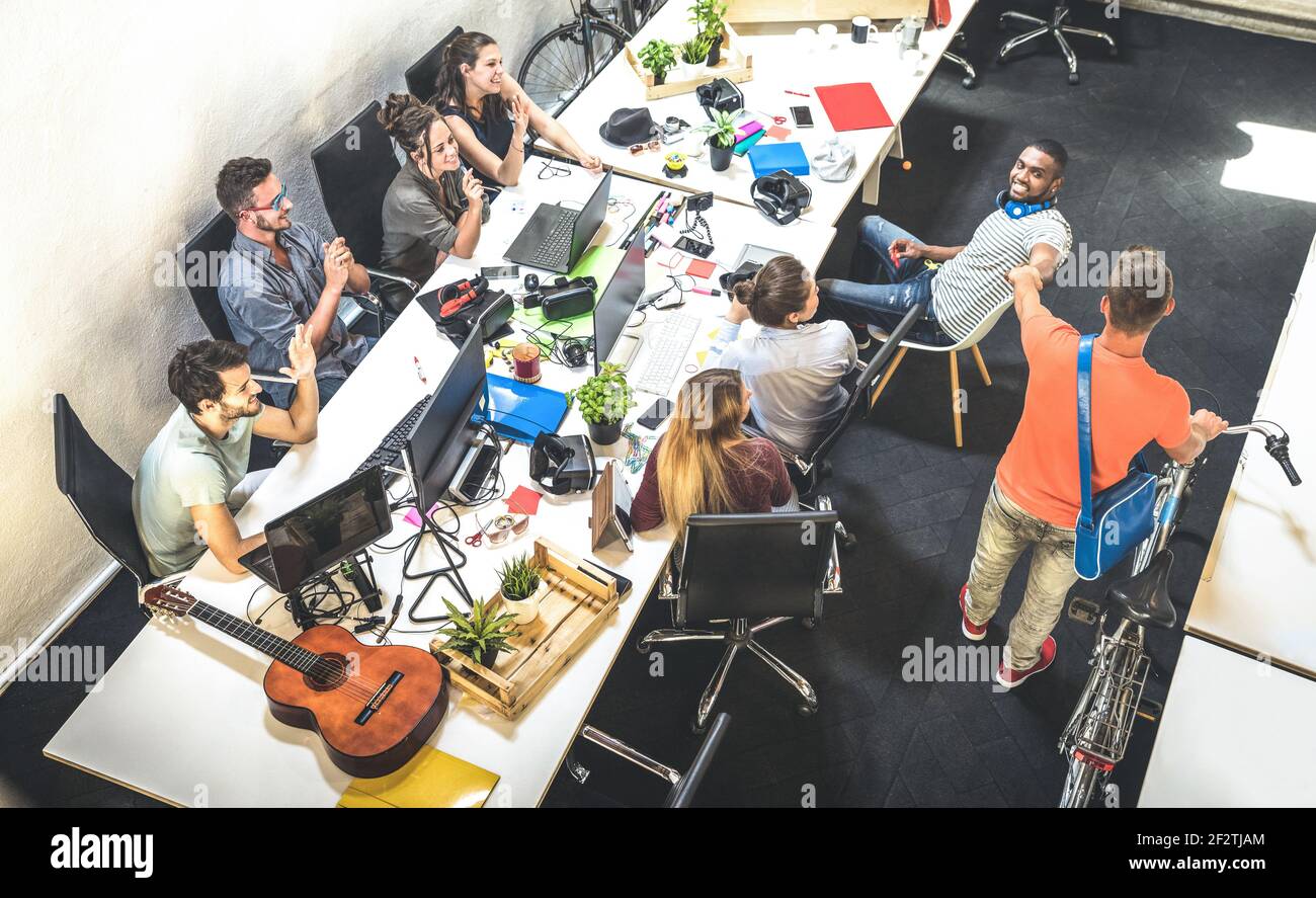 Gruppo di lavoratori dipendenti che si divertono in uno studio urbano alternativo con Giovane imprenditore che entra con moto d'epoca - Business Concept di risorsa umana Foto Stock