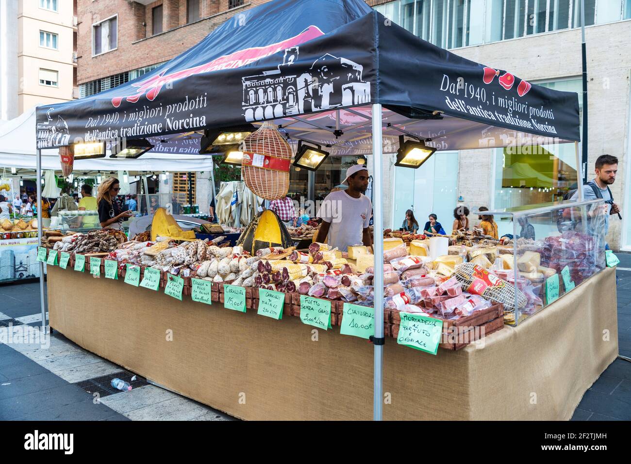 Napoli, Italia - 9 settembre 2019: Venditore in un negozio di formaggi e salsicce in un mercato di Street food con persone in giro in Via Toledo, Napoli, Italia Foto Stock