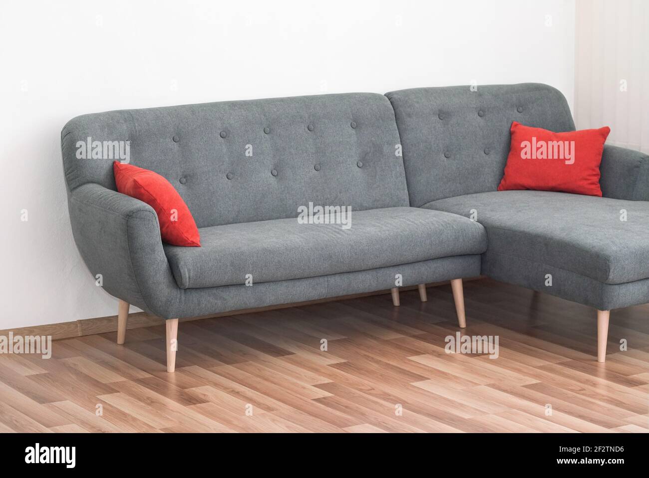 Moderno divano grigio con cuscini rossi su pavimento piastrellato in legno  - arredi da ufficio Foto stock - Alamy