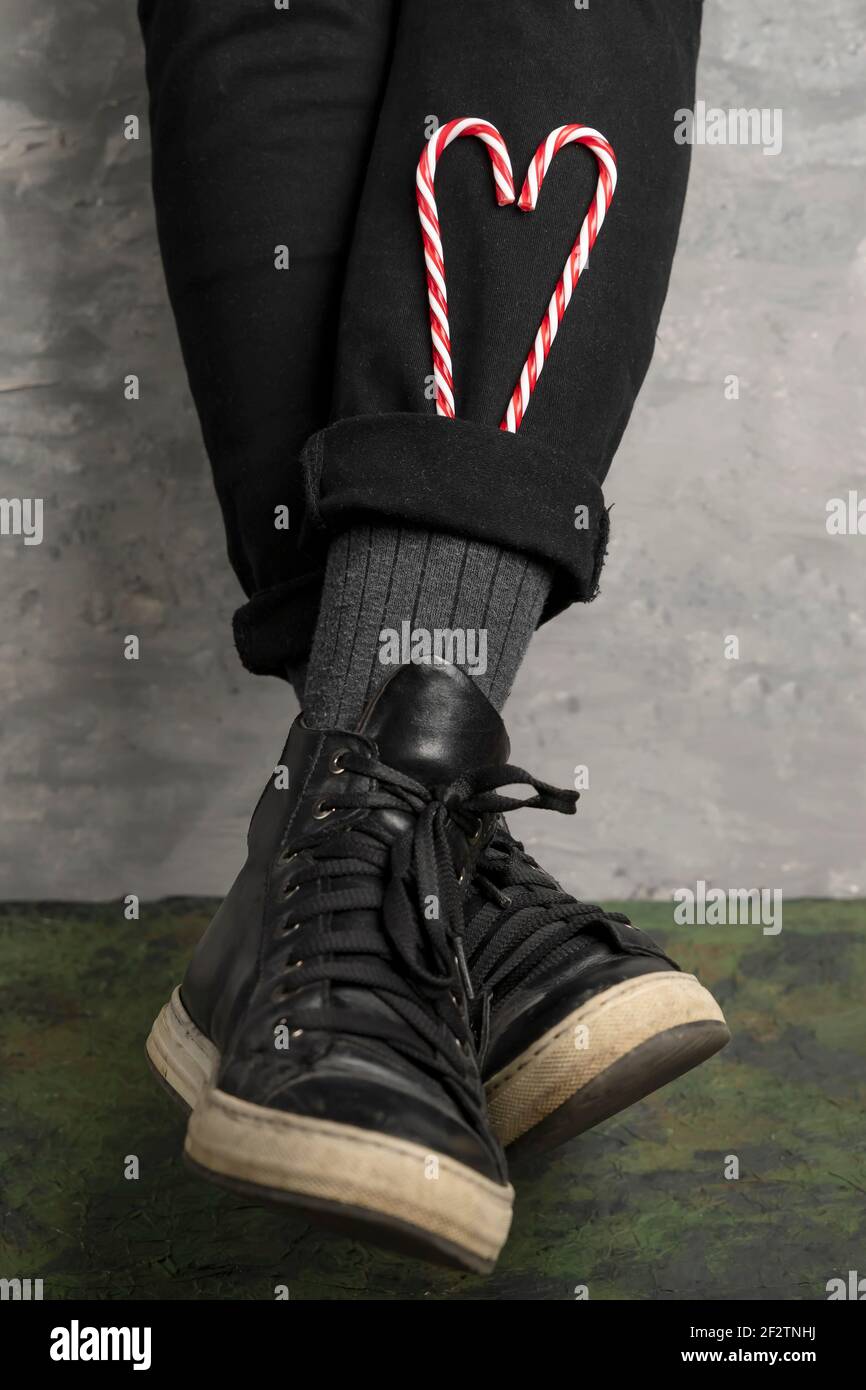 Una donna ha inserito due canne caramelle a forma di cuore nei polsini dei suoi pantaloni Foto Stock