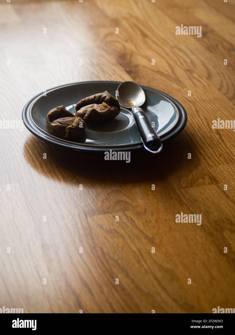 Piattino, bustine di tè usate, cucchiaino da tè su piano di lavoro di cucina in quercia Foto Stock