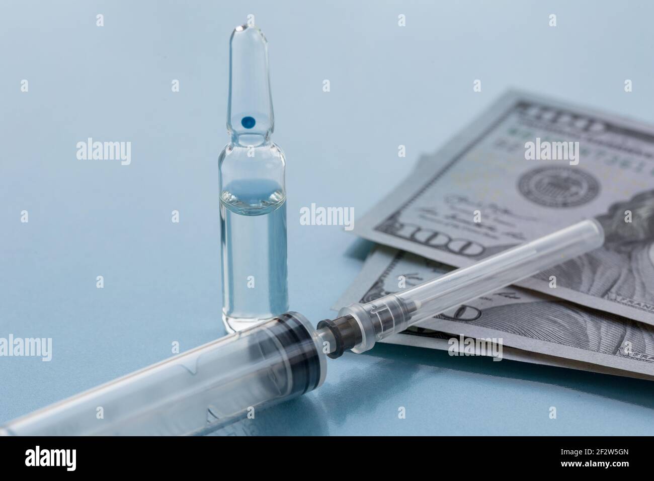 Ampollas, siringa estraibile per la vaccinazione e carta di denaro. Il concetto di medicina di assicurazione, costo elevato delle droghe. Isolato su sfondo blu. Foto Stock