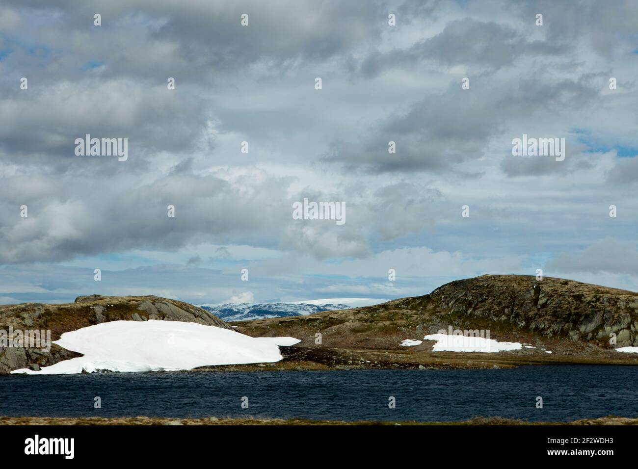 Neve fusa e lago tra le scogliere con neve estiva In cima alla Stordalsnippa, vicino a Roeldal in Norvegia Foto Stock