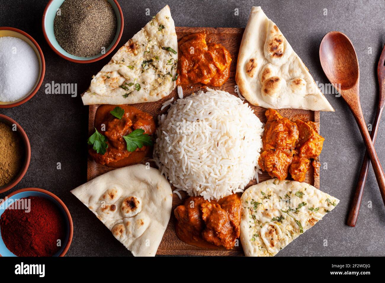 Piatto immagine della cucina indiana tradizionale piatto su sfondo scuro con spezie ed erbe sul lato. L'assortimento contiene anche pane naan Foto Stock