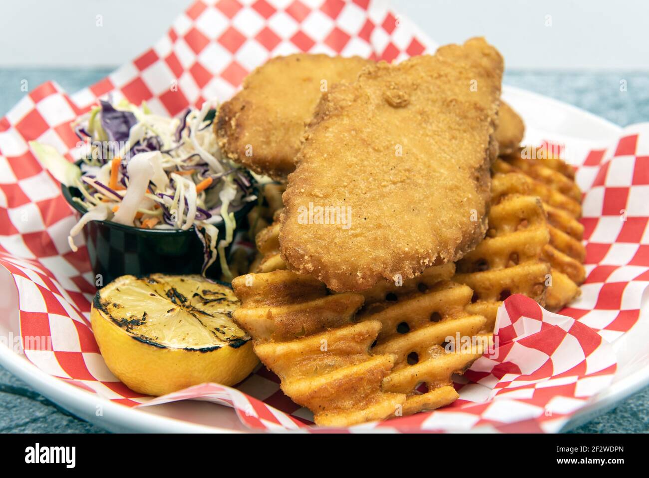 Pesce e patatine calde della friggitrice serviti con waffle fritte e costolette. Foto Stock