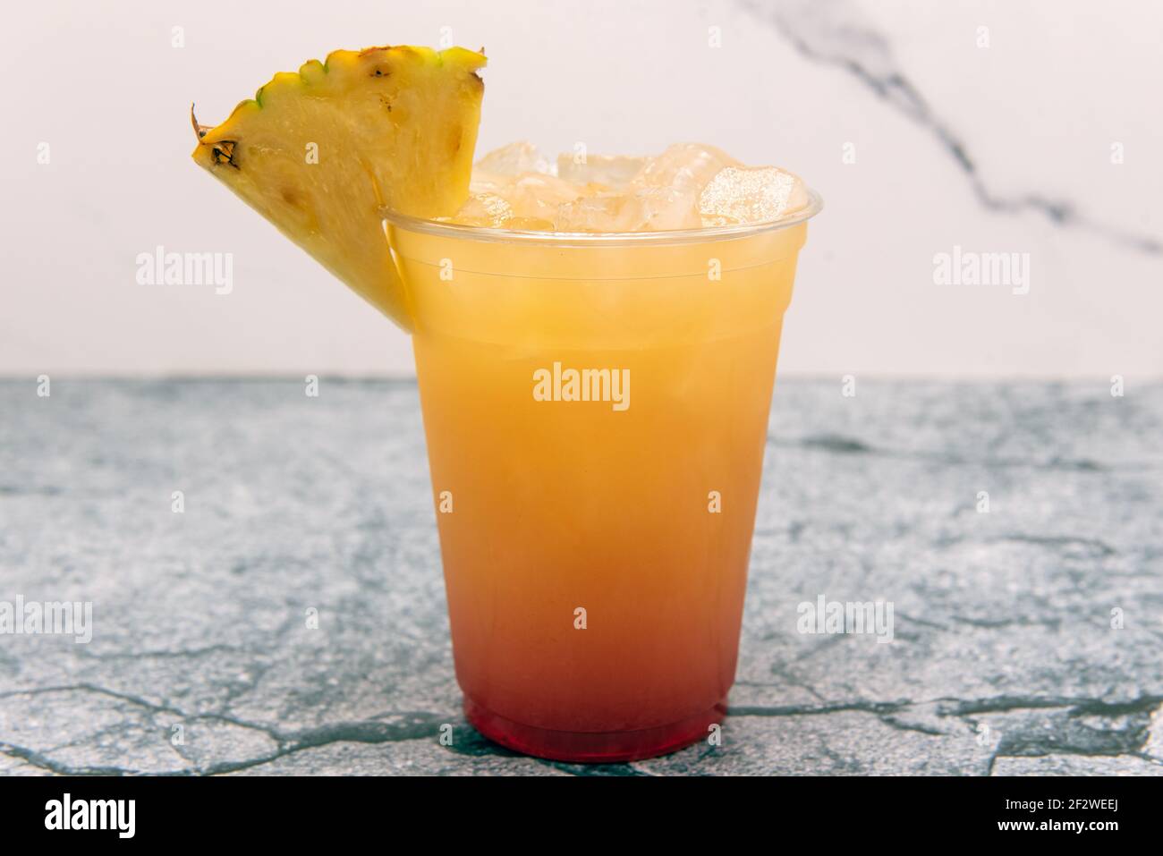 Cocktail di bevande miste che mostra il colore graduato degli ingredienti con la tazza guarnita con ananas per la presentazione. Foto Stock