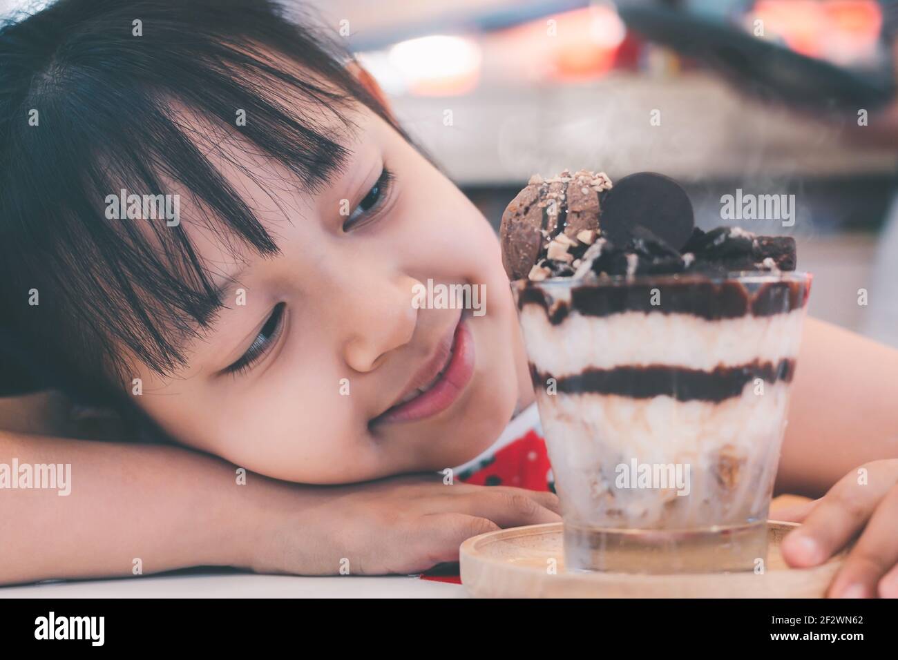 Carino bambina che guarda e sorride al gelato Foto Stock