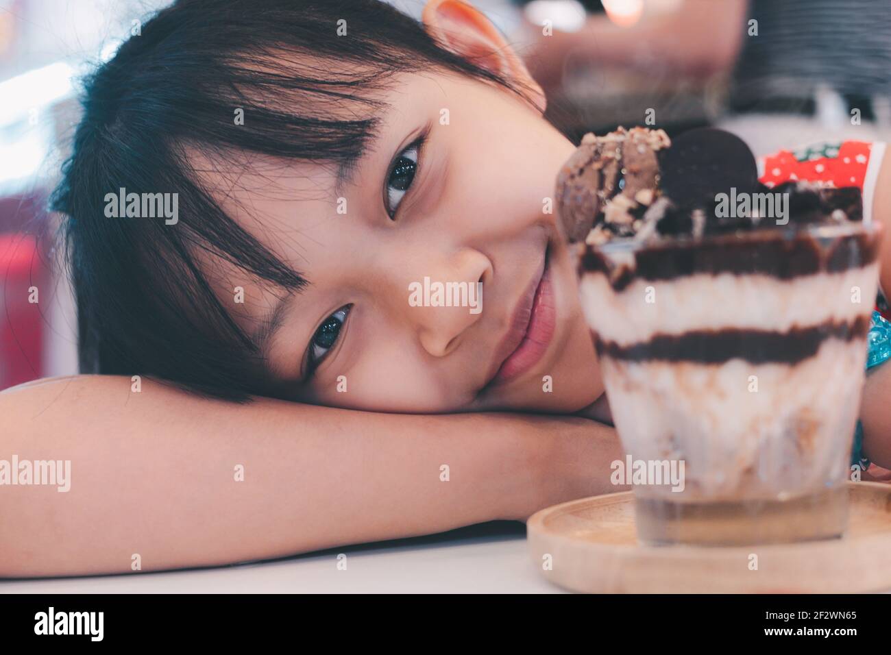 Carino bambina che guarda e sorride al gelato Foto Stock