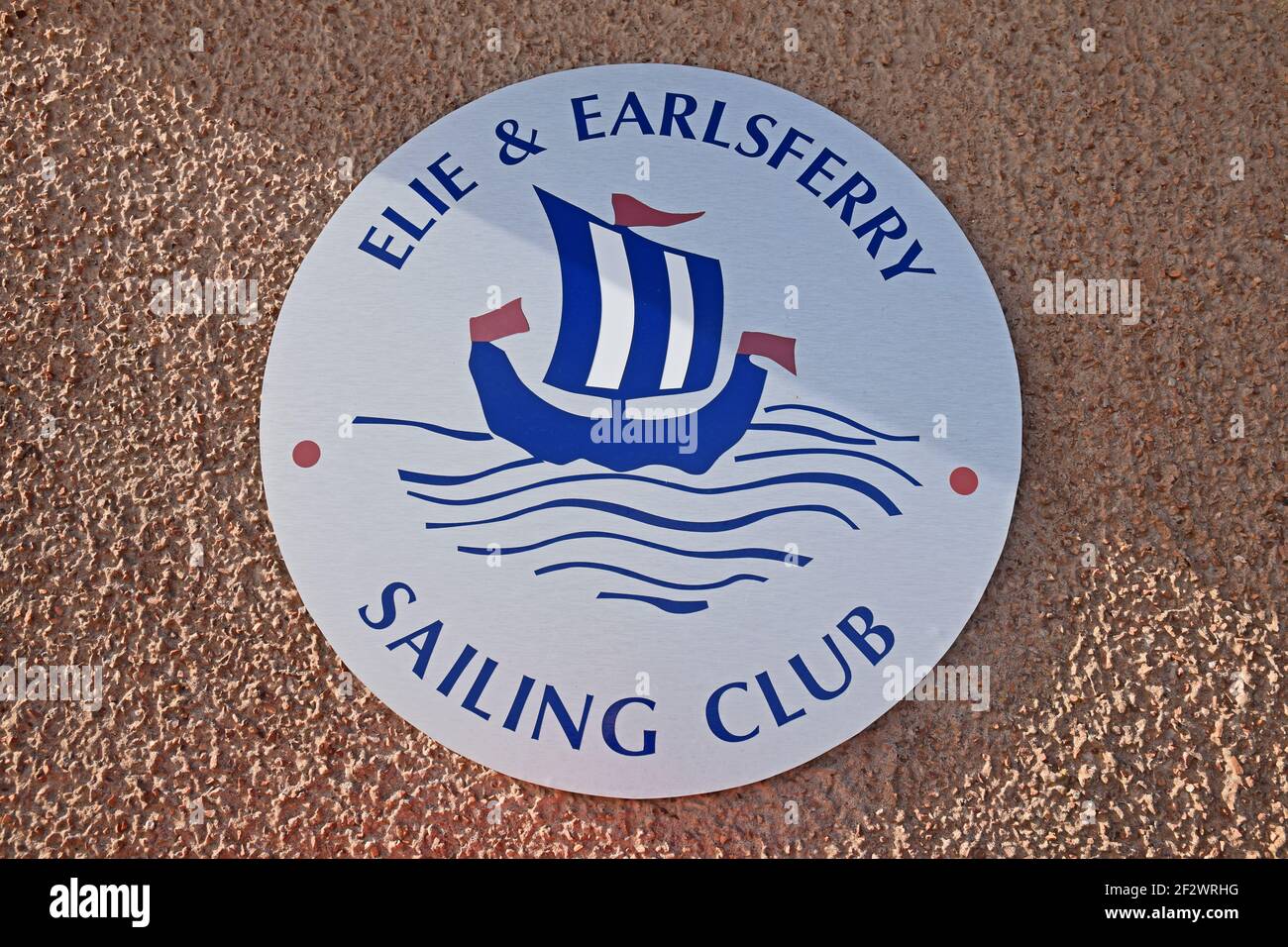 Cartello Elie e Earlsferry Sailing Club, isolato su parete piana. Cartello circolare con logo della barca a vela sulle onde. Fife, Scozia, Regno Unito. Foto Stock