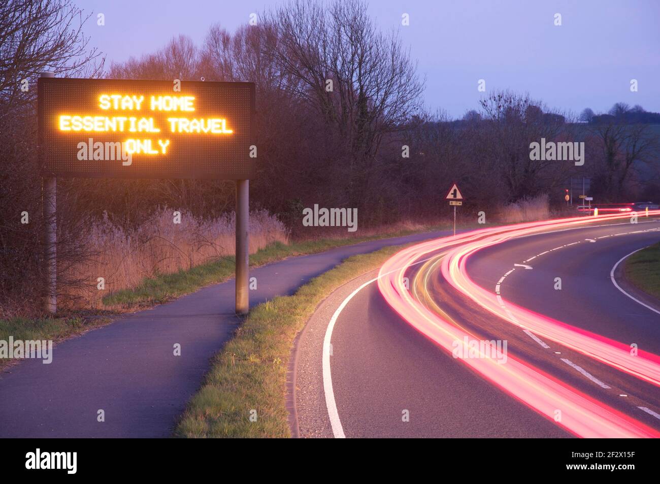 "Rimani a casa solo per i viaggi essenziali". Segnaletica stradale con display a matrice di punti elettronico che consiglia la conformità alle norme di blocco pandemiche Covid 19. Inghilterra, Regno Unito. Foto Stock
