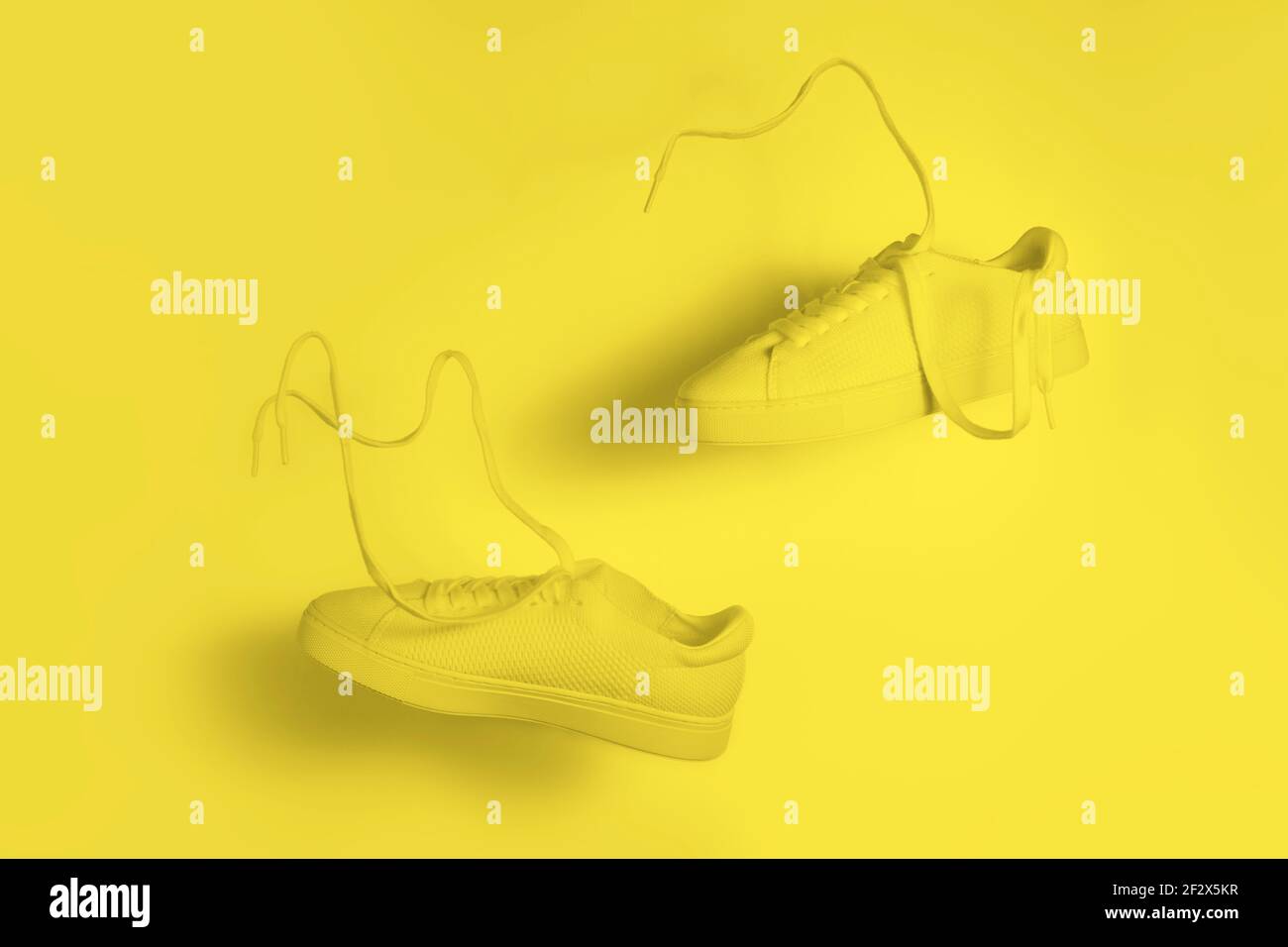 il concetto di leggerezza e leggerezza. un paio di sneaker gialle che volano in aria su uno sfondo giallo Foto Stock