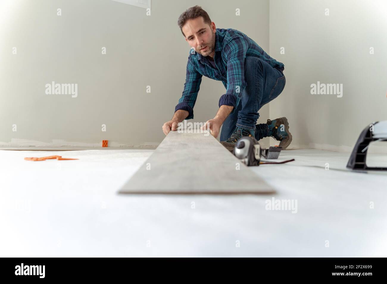 closeup di un uomo che tiene un foglio di legno a. installare il pavimento della casa Foto Stock