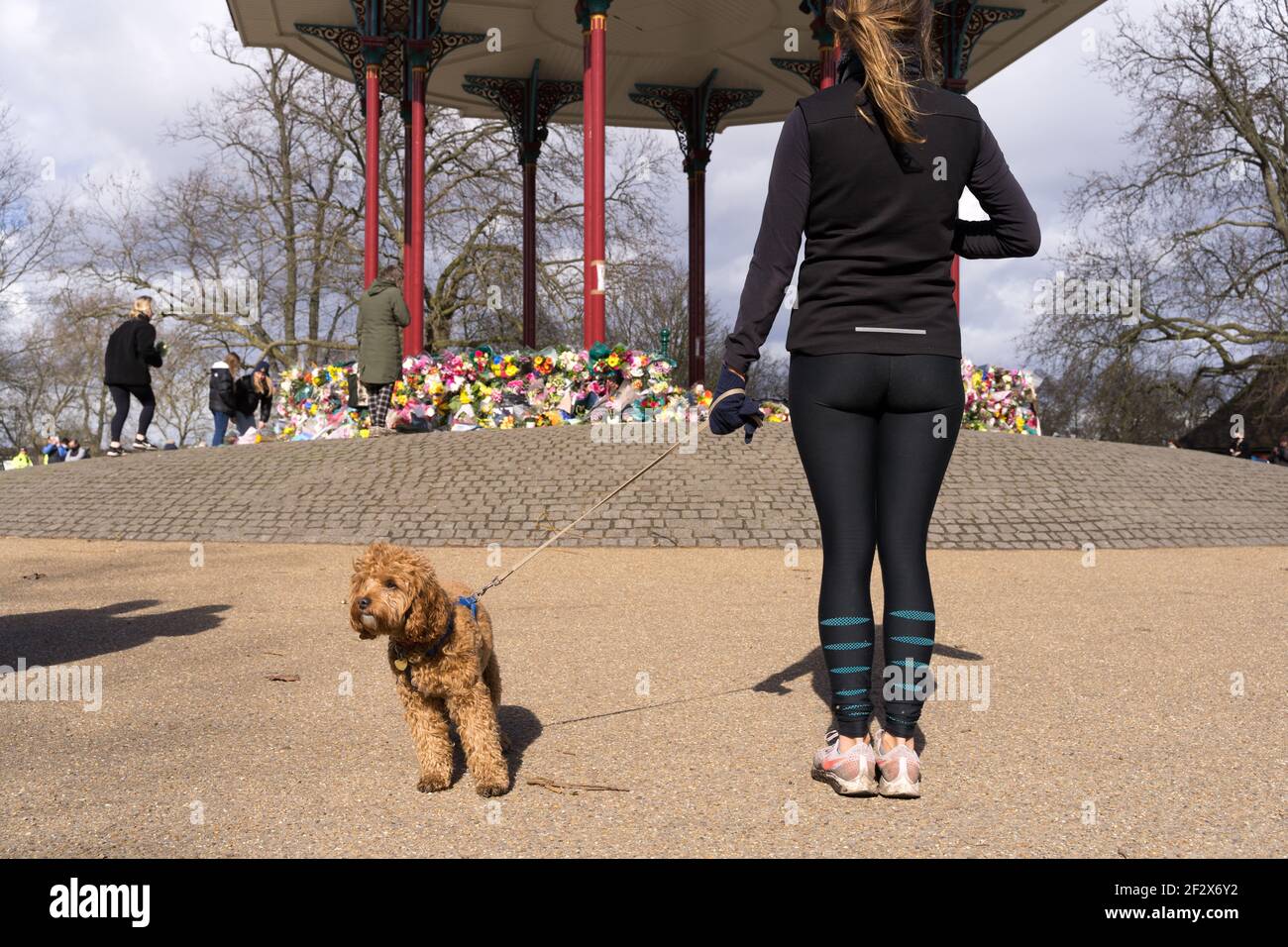 Le donne conducono un cane pagano tributi floreali a Clapham comune bandstand in memoria di Sarah Everard, rapito e assassinato , Londra, Inghilterra Foto Stock