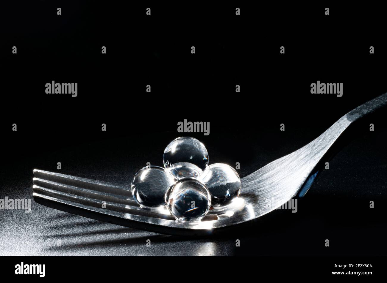Perle caviale grigie in forchetta metallica su sfondo nero macro vista con spazio di copia Foto Stock