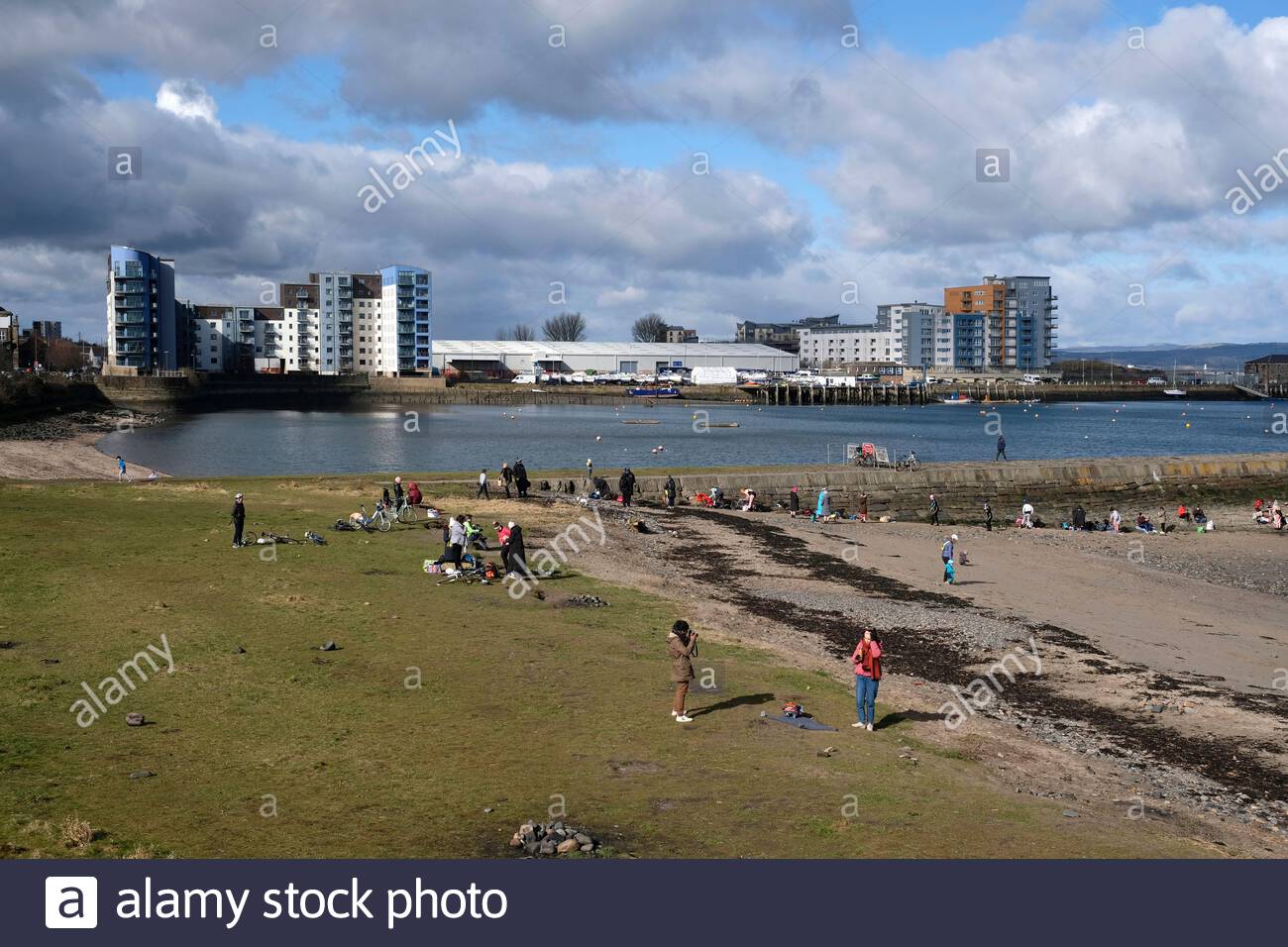 Le persone che si godono il frangiflutti del porto di Granton e la baia di Wardie in una giornata di sole, Edimburgo, Scozia Foto Stock